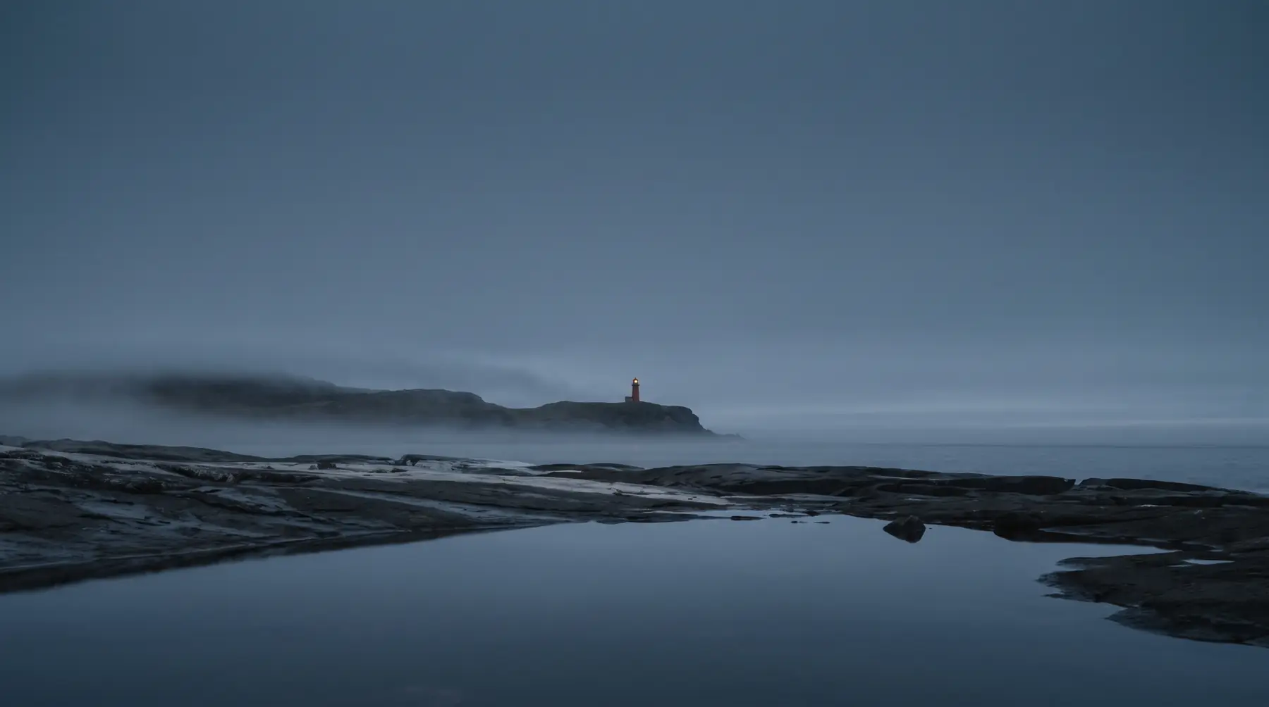 A lighthouse on a remote coastline at blue hour